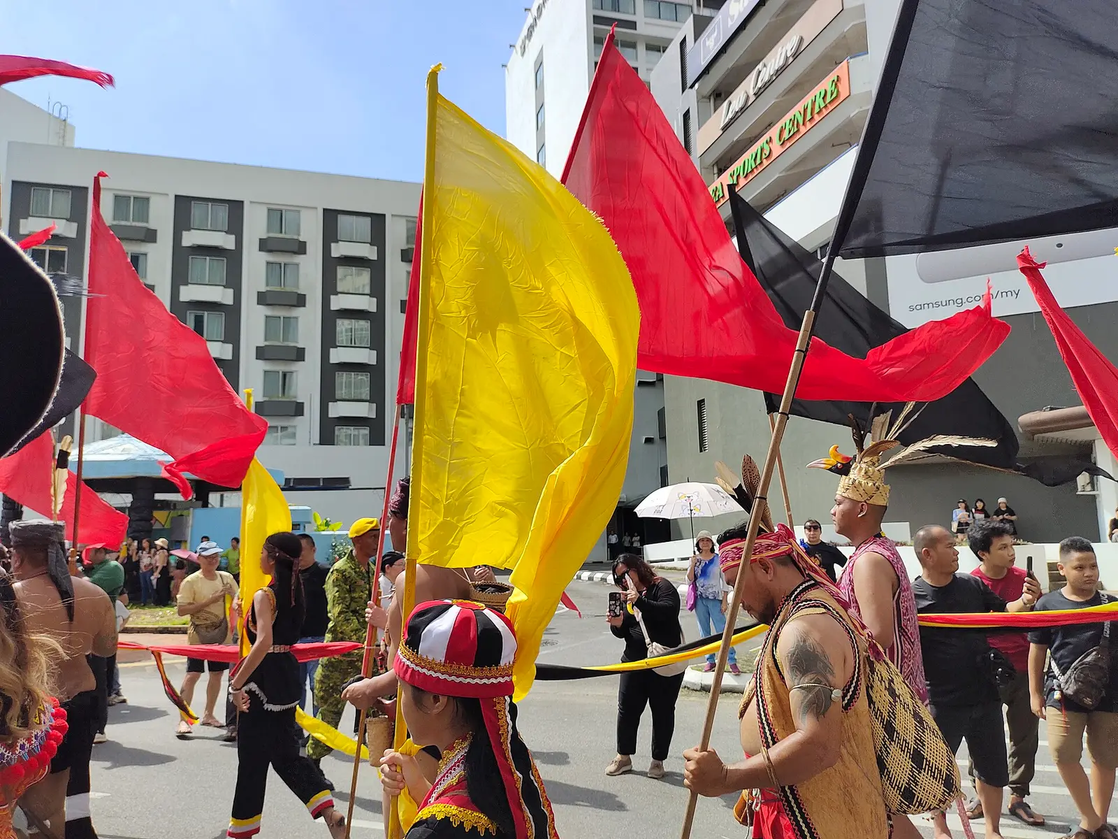 Participants in traditional dress carrying flags in the Gawai Dayak cultural parade in 2024